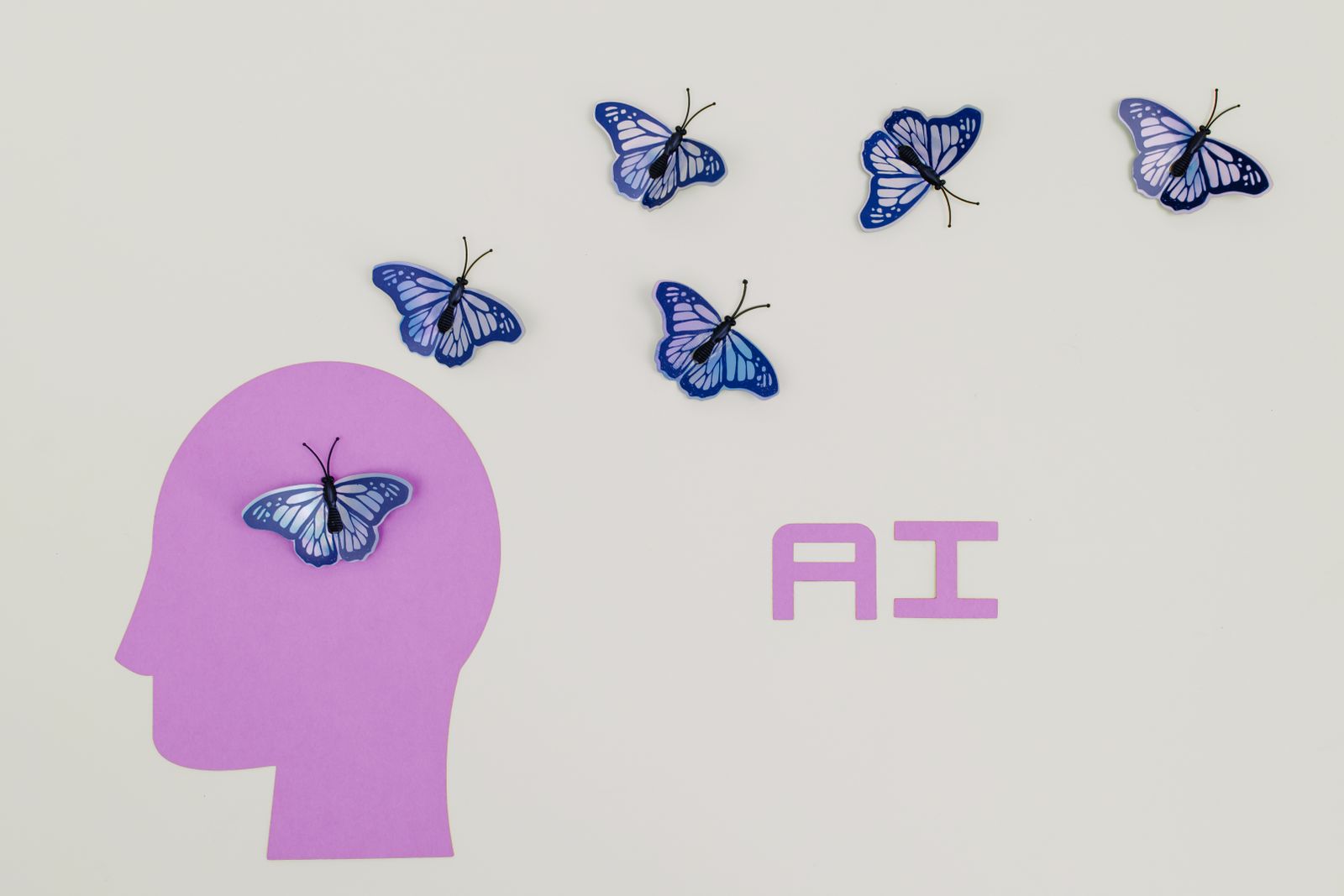 A paper profile of a head with butterflies and the word AI — separating the subject and silhouette