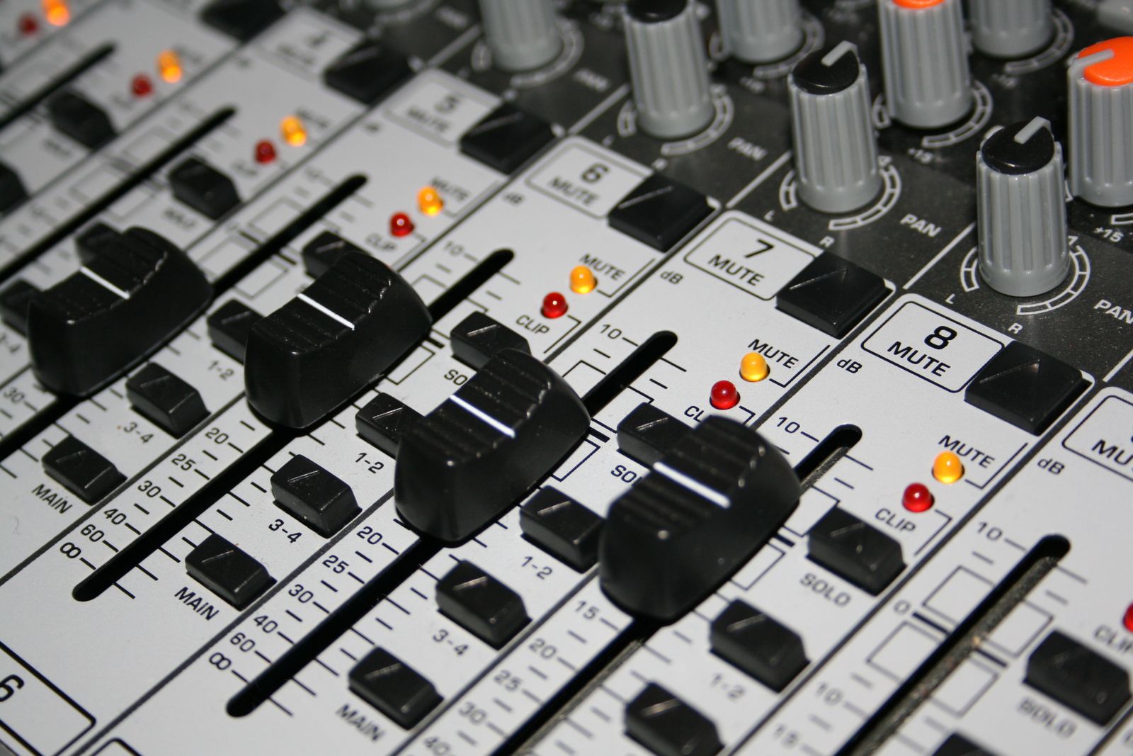 Close-up of mixing console faders labeled MUTE, CLIP, SOLO and a decibel scale