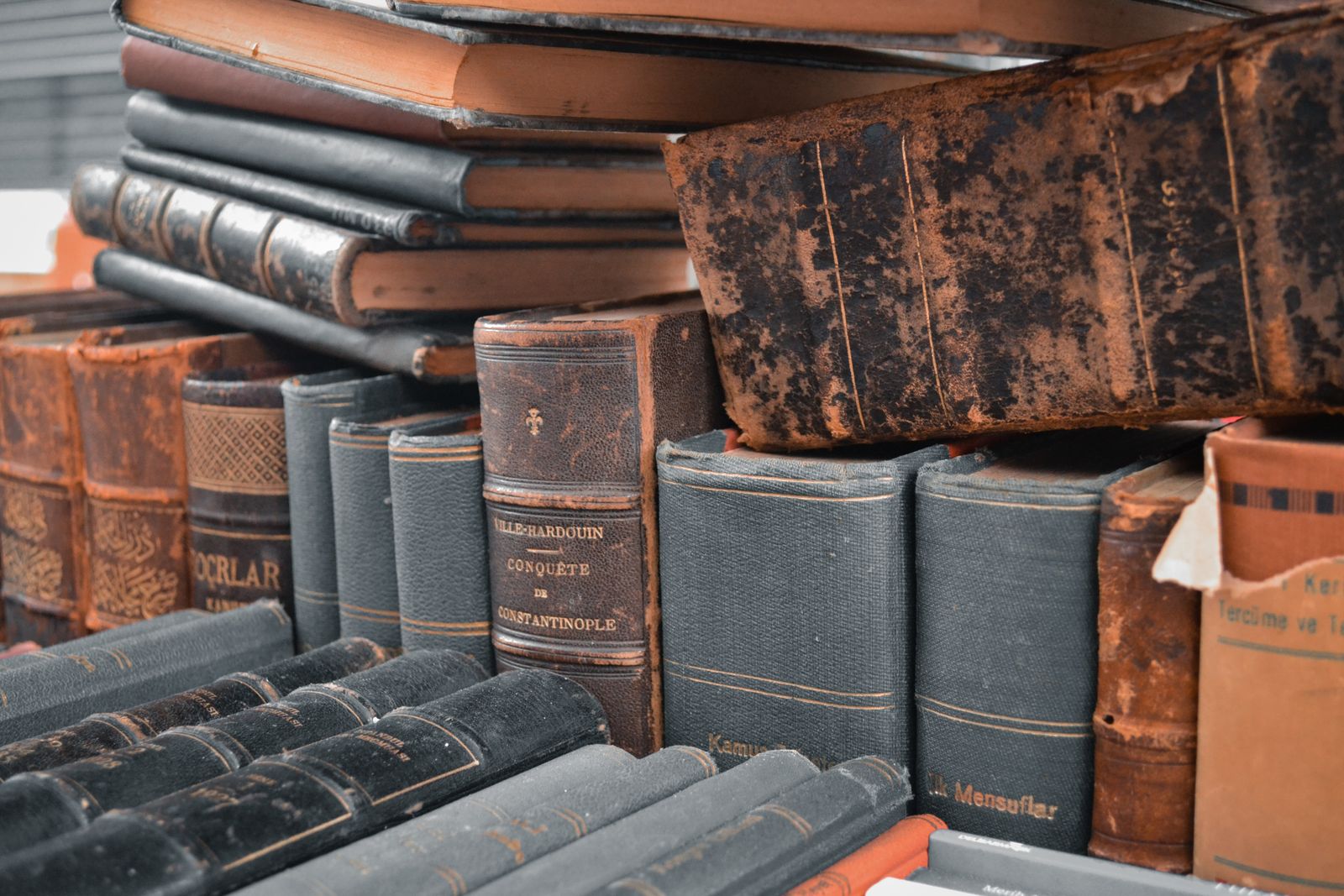 Стопки старых книг разного формата, сложенные на полках архива
