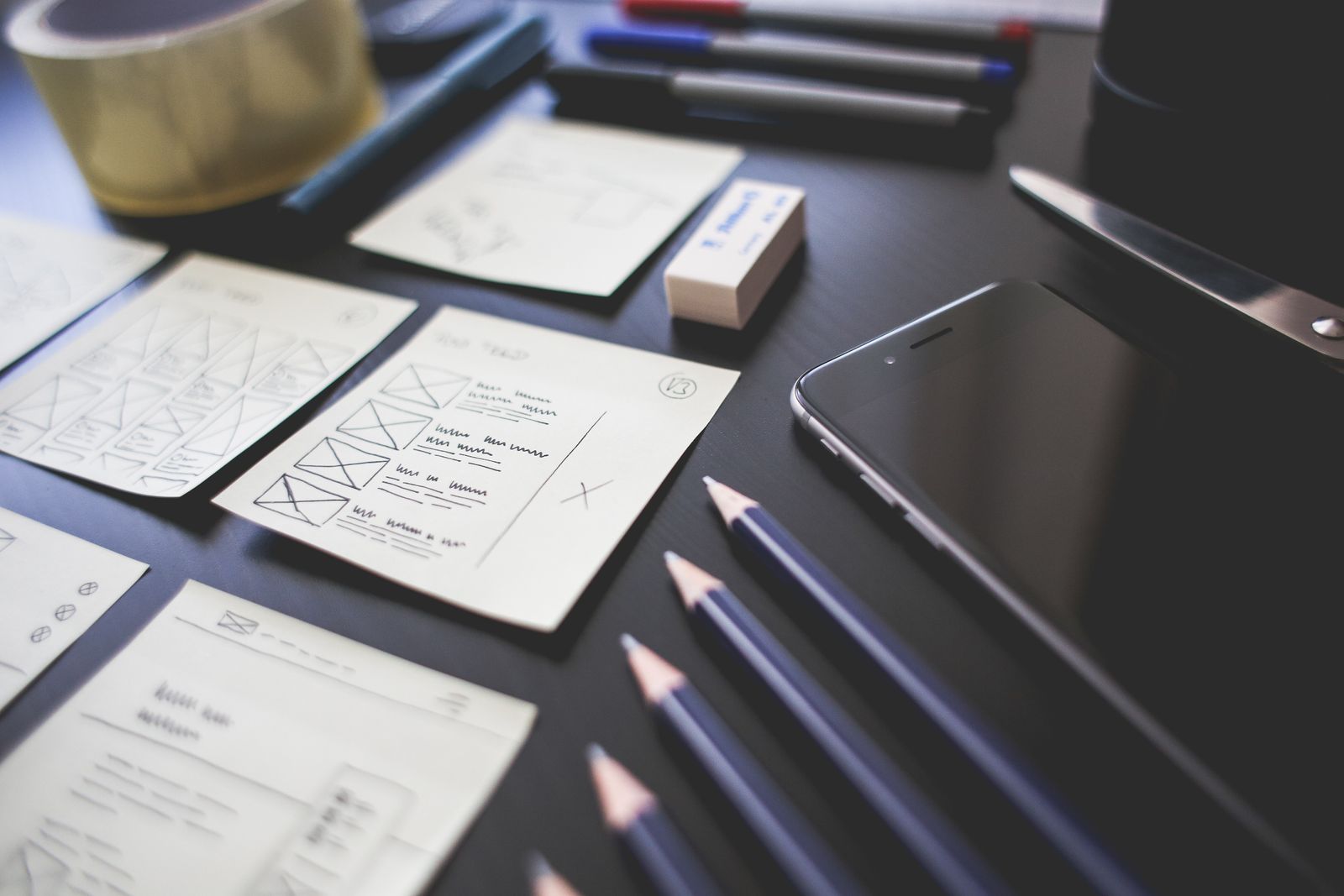 Interface sketches, pencils and a smartphone on a designer's desk