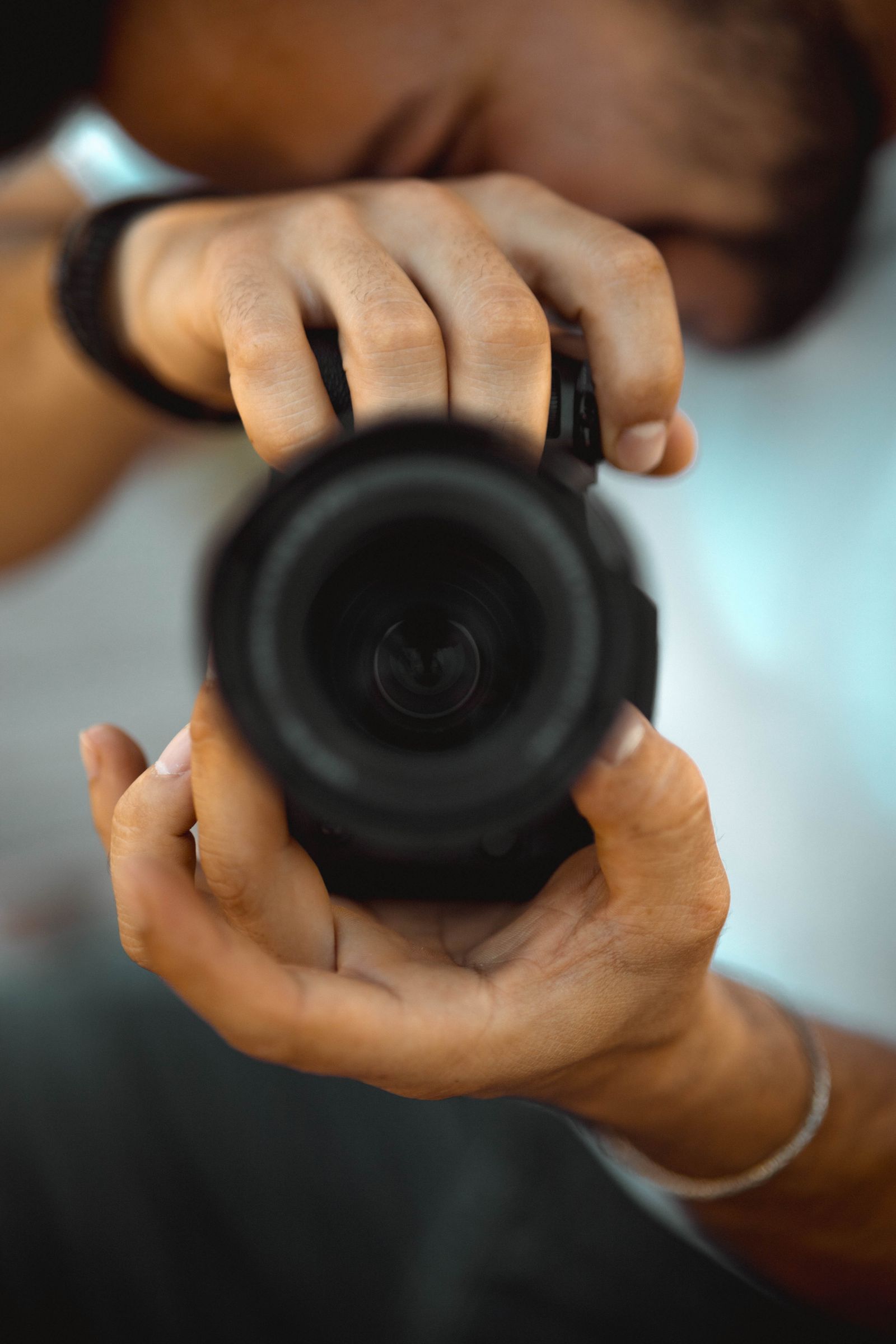 A photographer's hands holding a camera — shooting RAW means editing later