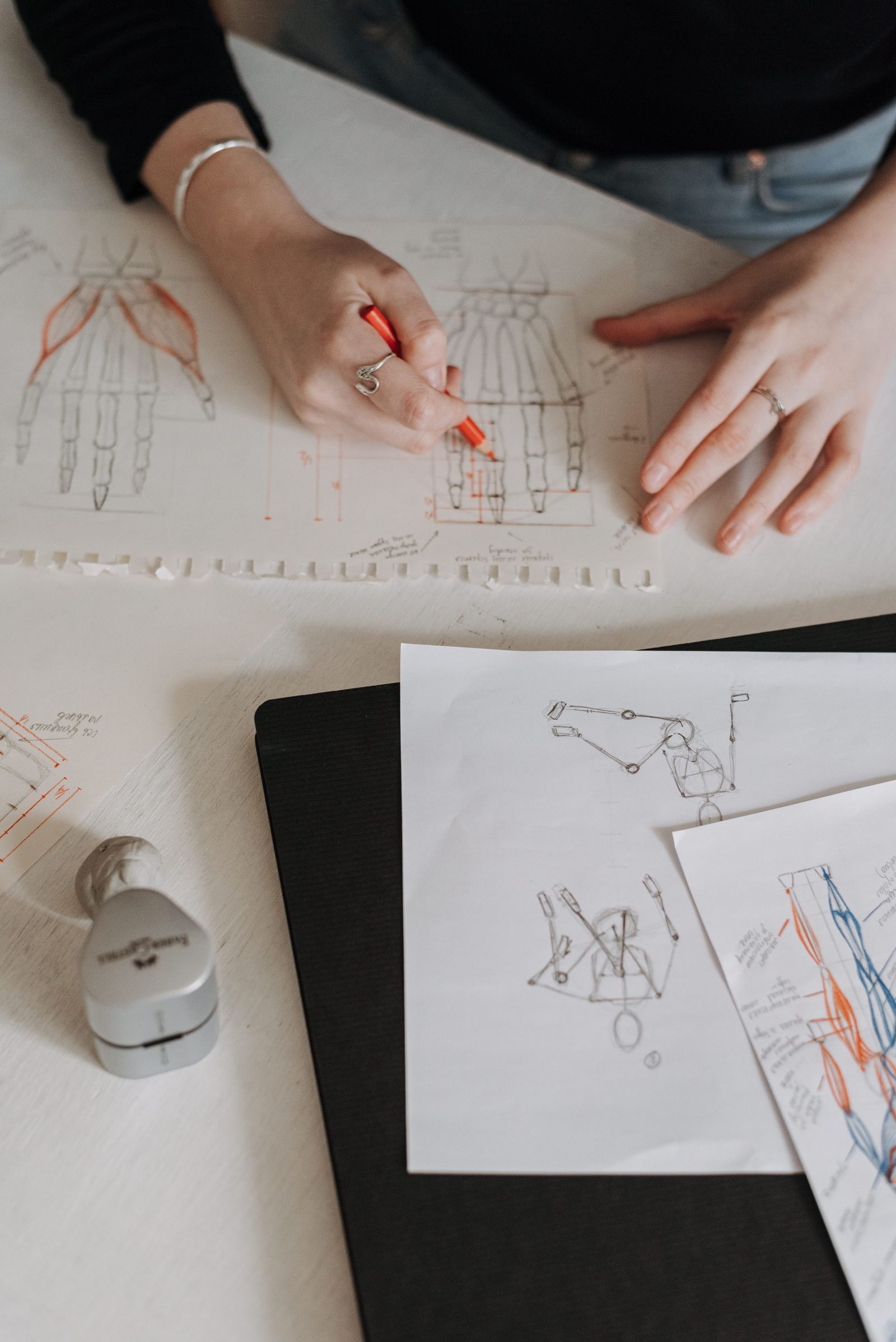A designer working through mark variations on paper — searching for the shape of a future vector logo