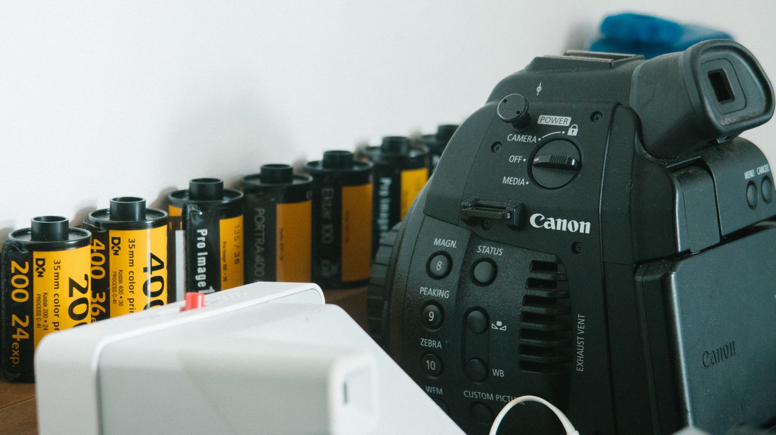 Кинокамера Canon Cinema EOS рядом с катушками цветной плёнки Kodak Portra и ProImage — переход от съёмки к цифровому файлу