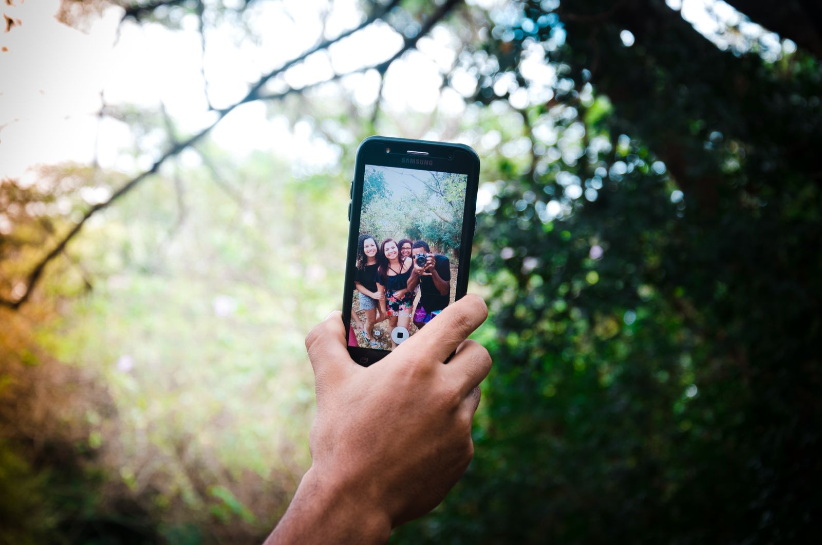 A person photographing friends on a smartphone — everyday shooting saved as HEIC
