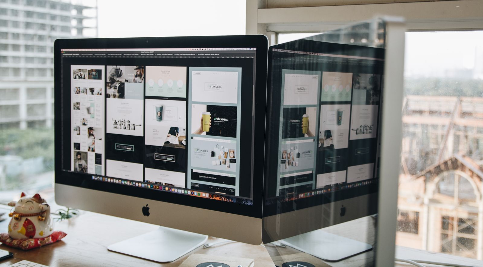 Two monitors showing web layouts — a web designer's workspace